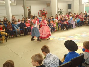Foto 1 - 1ª prendinha, Tábata e o peão Marion dançando para os alunos dos Anos Iniciais
